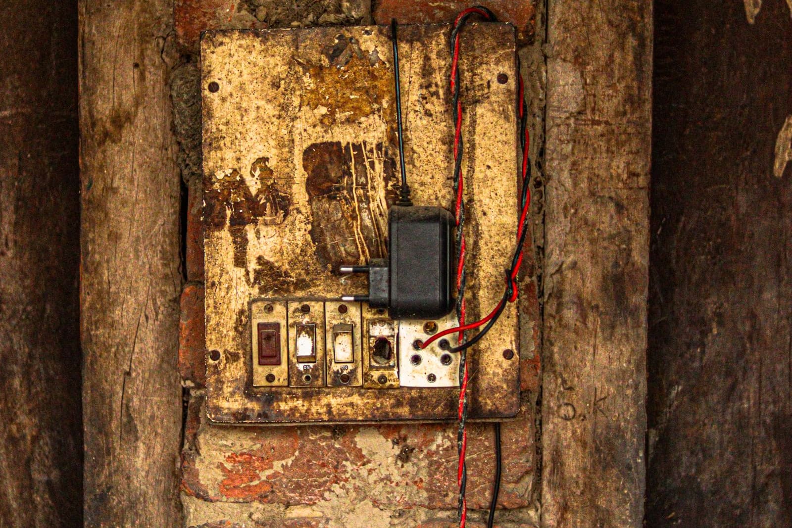 An old, rusted fuse box with exposed wiring